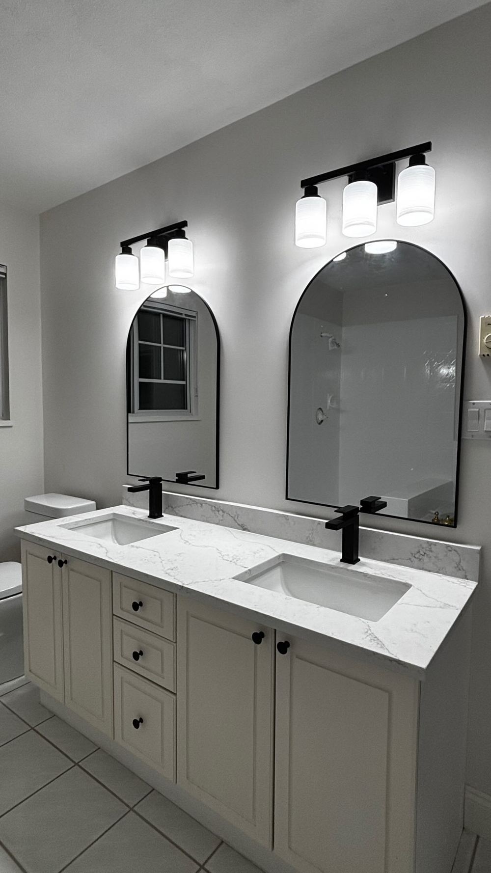 Bathroom upgraded by Lee's Custom Carpentry: double vanity, arched mirrors and new lighting