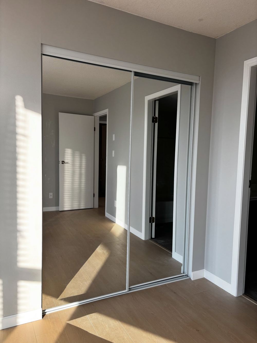 Downtown Vancouver condo bedroom with new flooring, paint and mirror closet doors